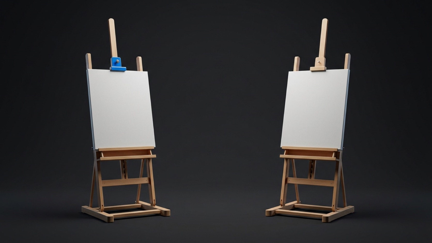 Two identical wooden easels holding blank canvases side by side in a dark studio